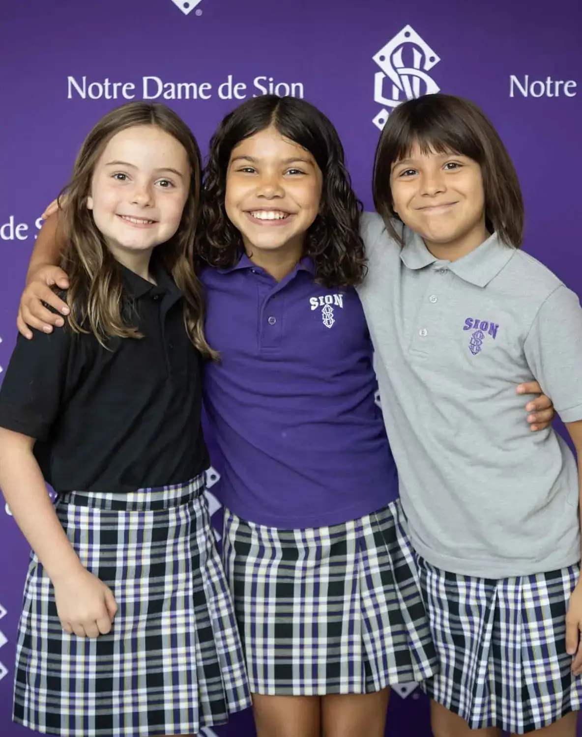 Notre Dame de Sion students smiling arm in arm.