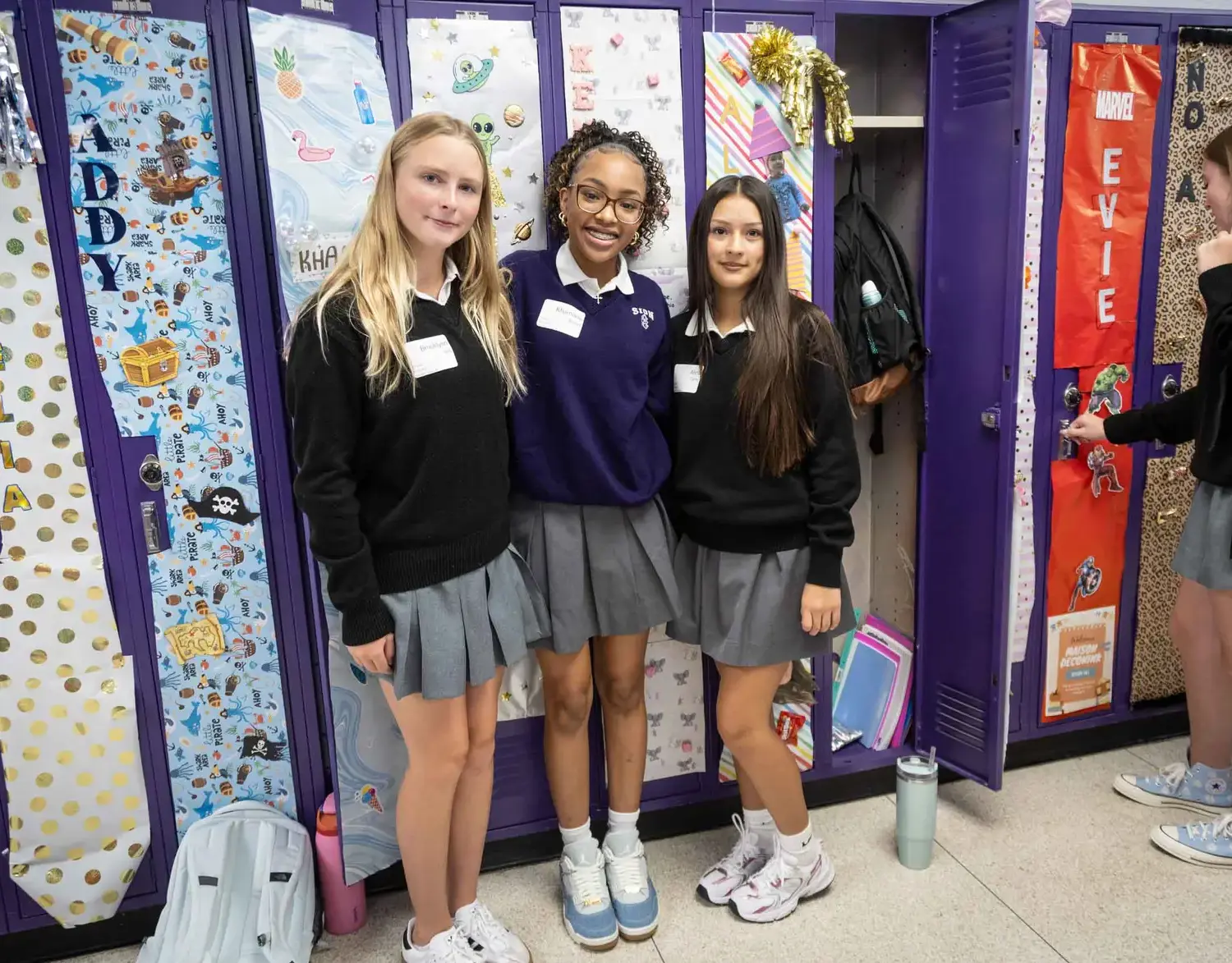 Notre Dame de Sion Grade School students smiling arm in arm in front of a display of student artwork.