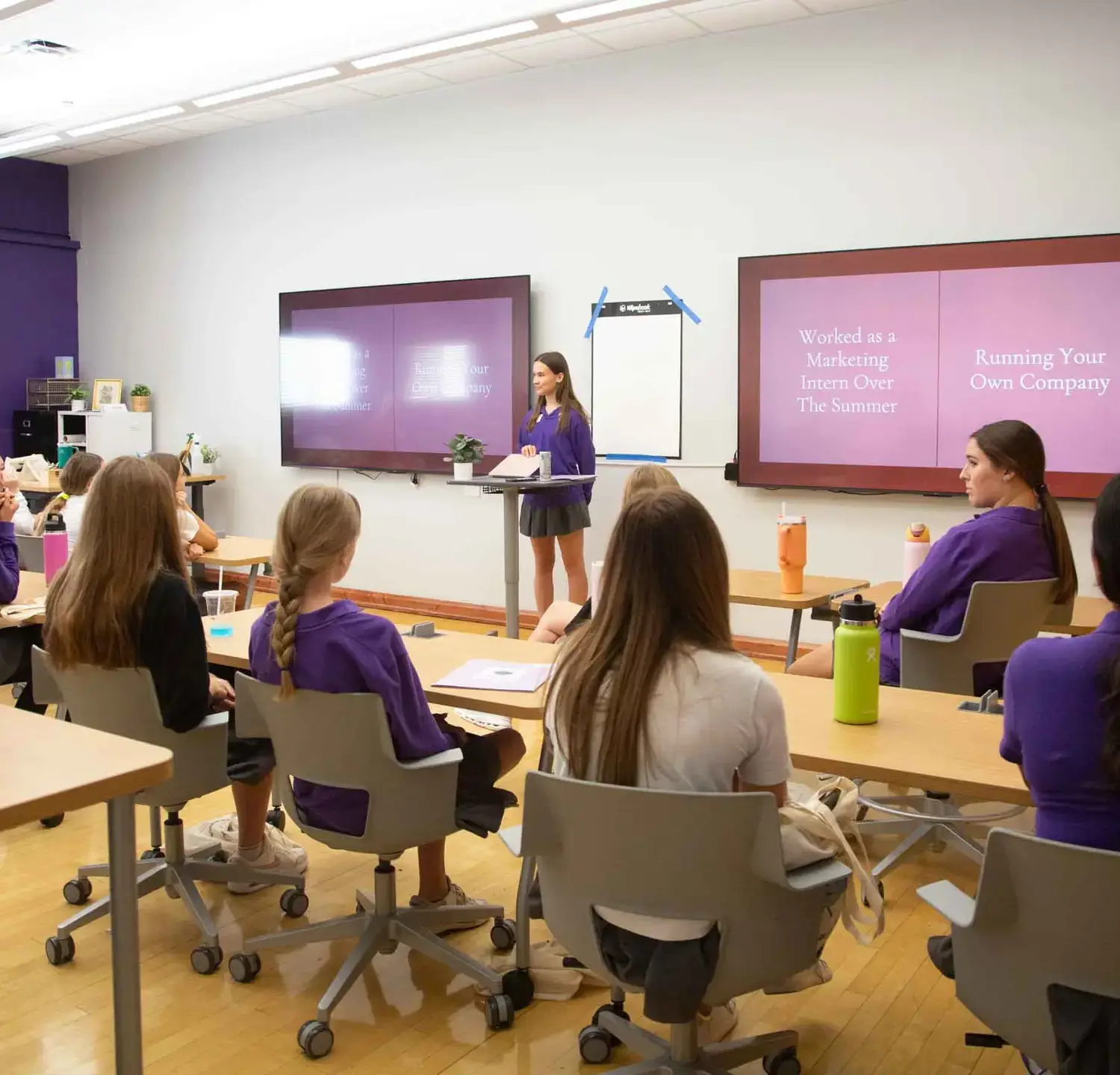 Notre Dame de Sion High School students in class, listening attentively to their classmate giving a presentation.