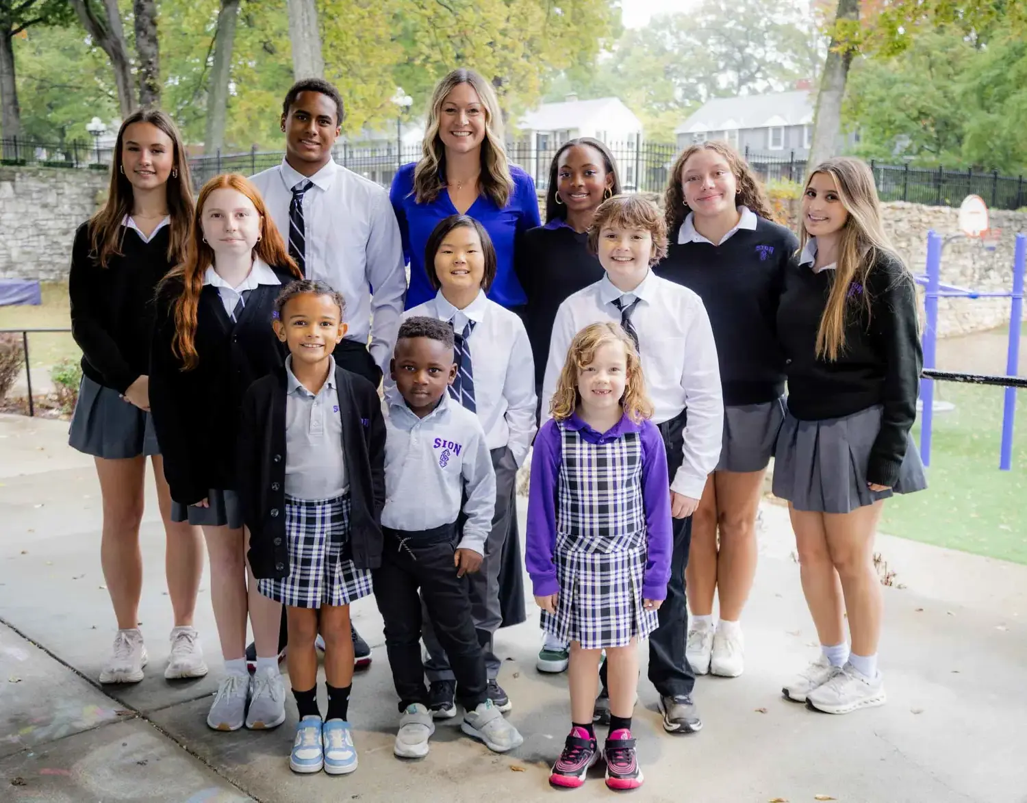 Notre Dame de Sion dual campus students smiling together for a photograph with the school president.