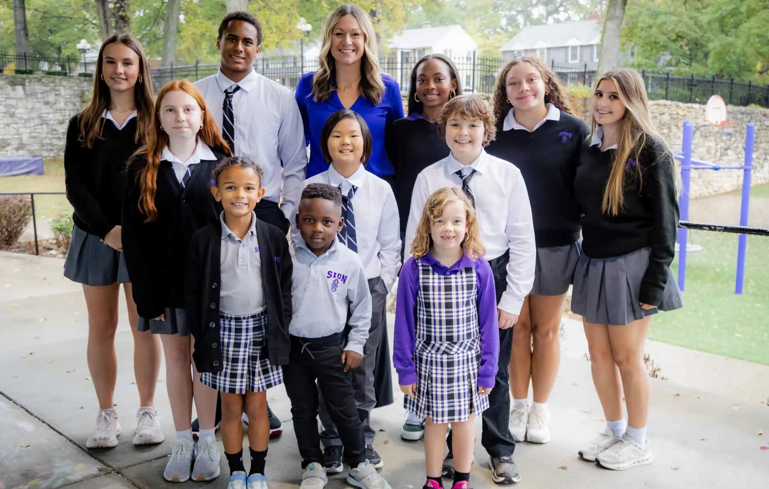 Notre Dame de Sion students of all ages smiling for a photograph together with the president.