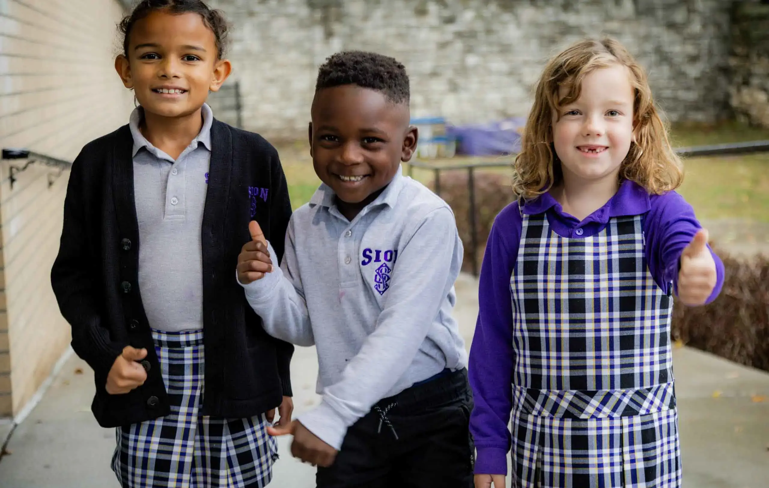 Notre Dame de Sion Grade School students smiling brightly, giving thumbs up.