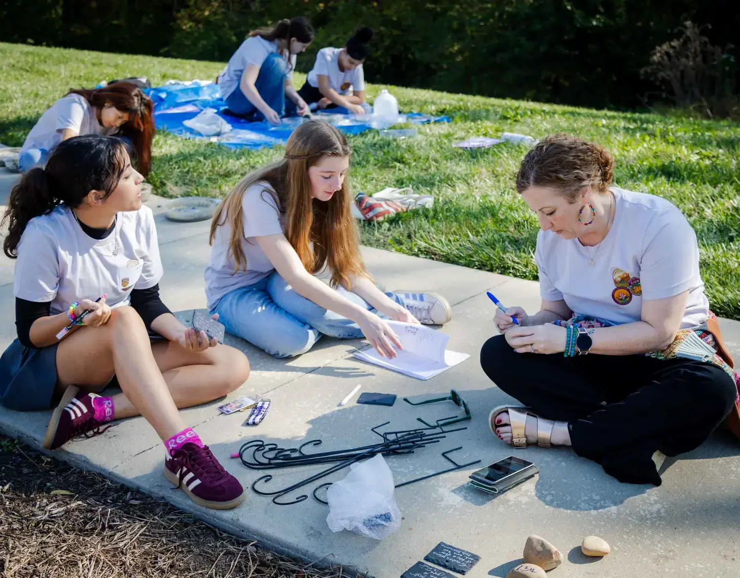 Notre Dame de Sion students working on a project outside in the sunshine with a teacher.