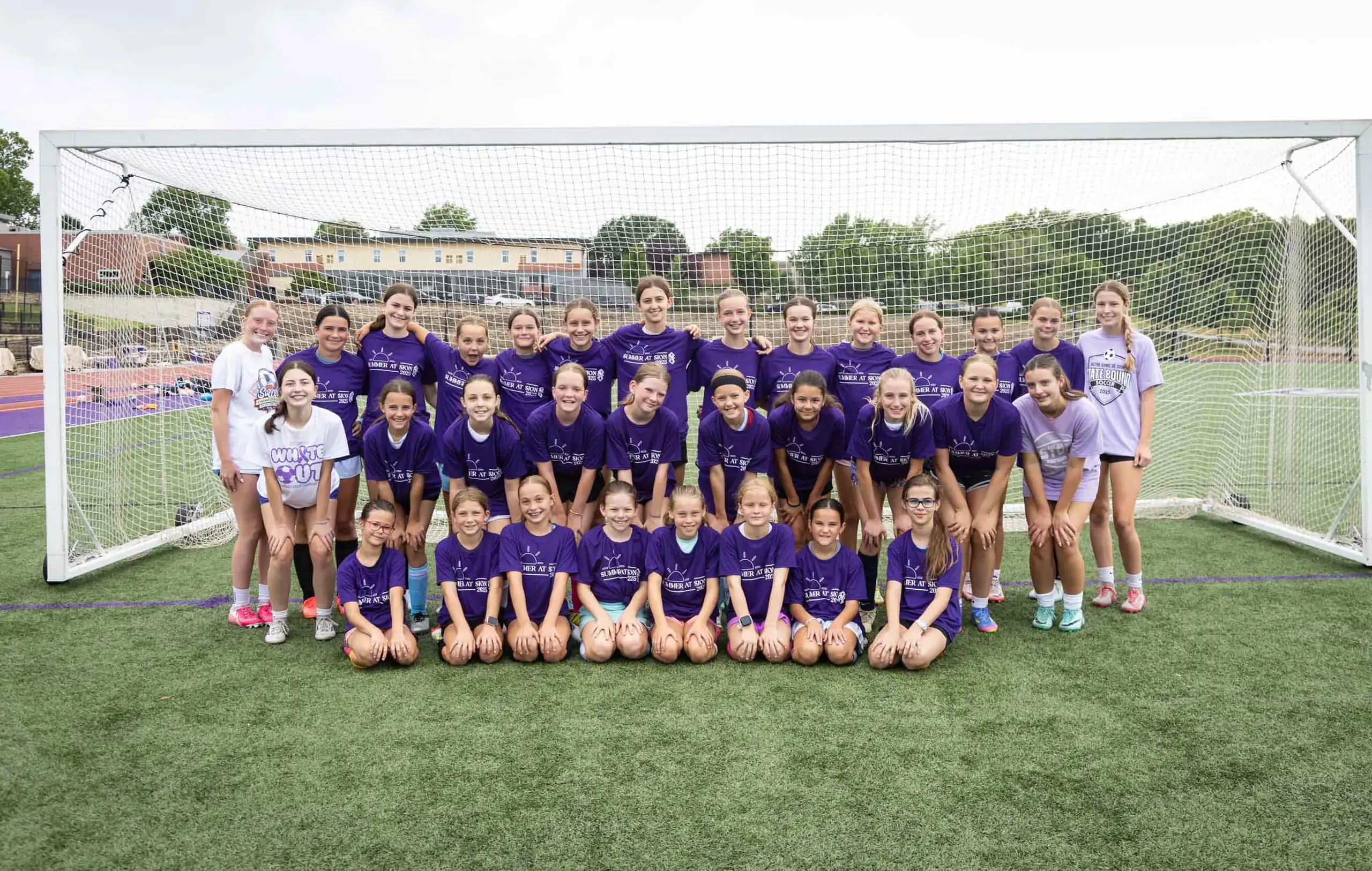 Notre Dame de Sion Summer Camp attendees group photograph on soccer pitch.