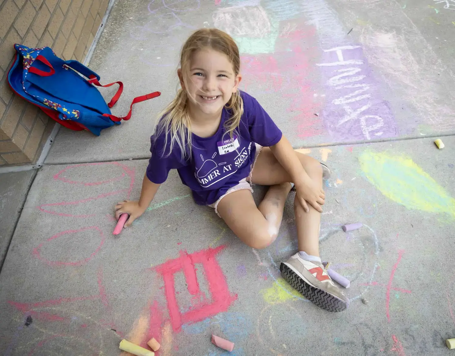 Notre Dame de Sion Grade School Summer Camp attendee drawing on the pavement with chalk.