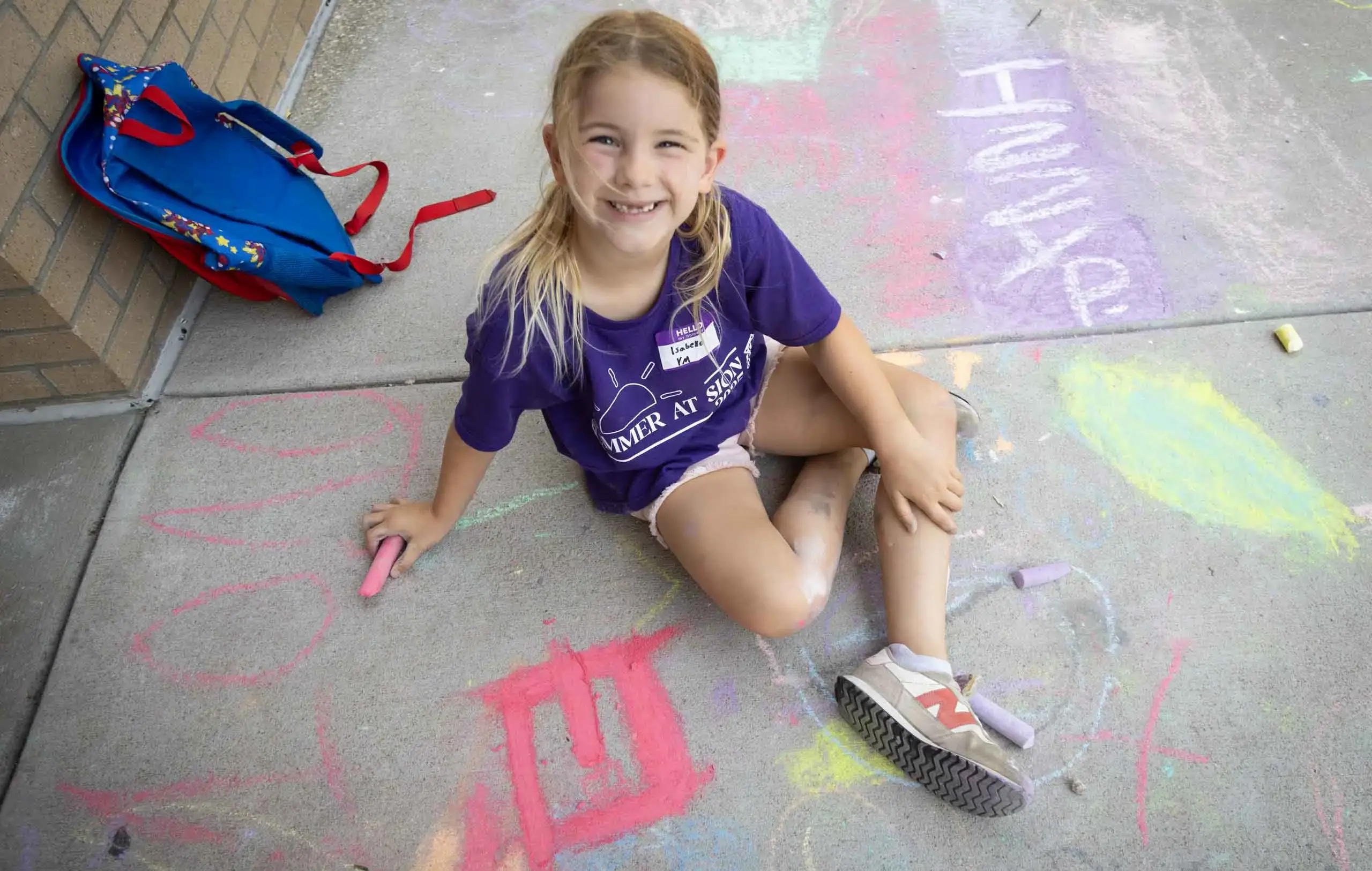 Notre Dame de Sion Grade School Summer Camp attendee drawing on the pavement with chalk.