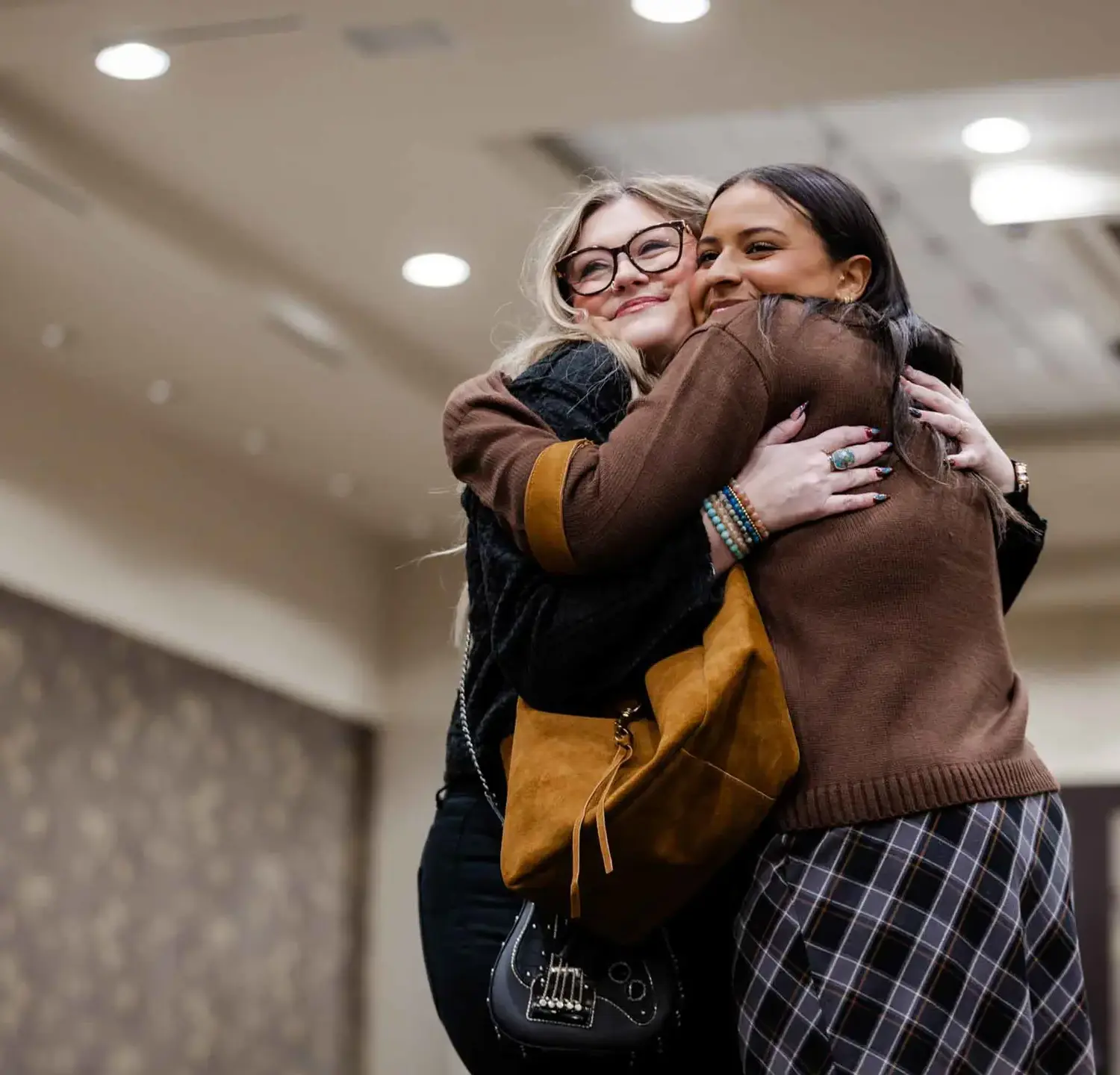 Notre Dame de Sion High School student and their mother hugging, smiling elatedly, at Mother-Daughter Brunch & Fashion Show.