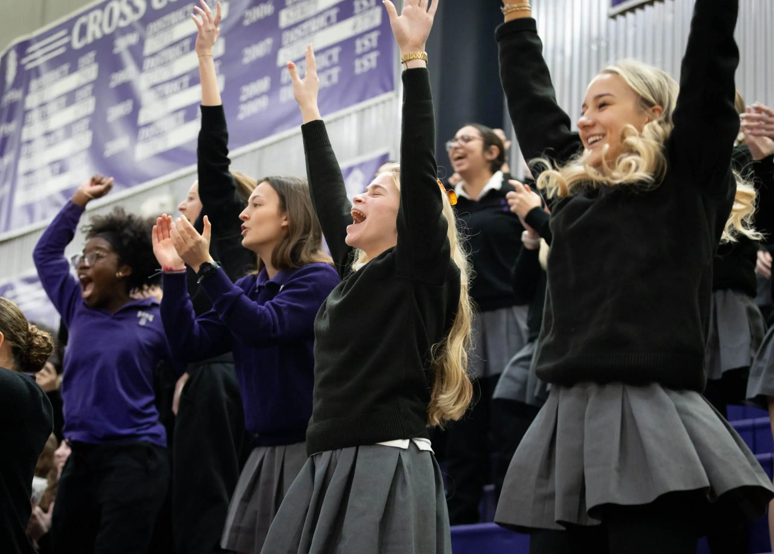 Notre Dame de Sion High School students cheering at an athletics game in the gym.