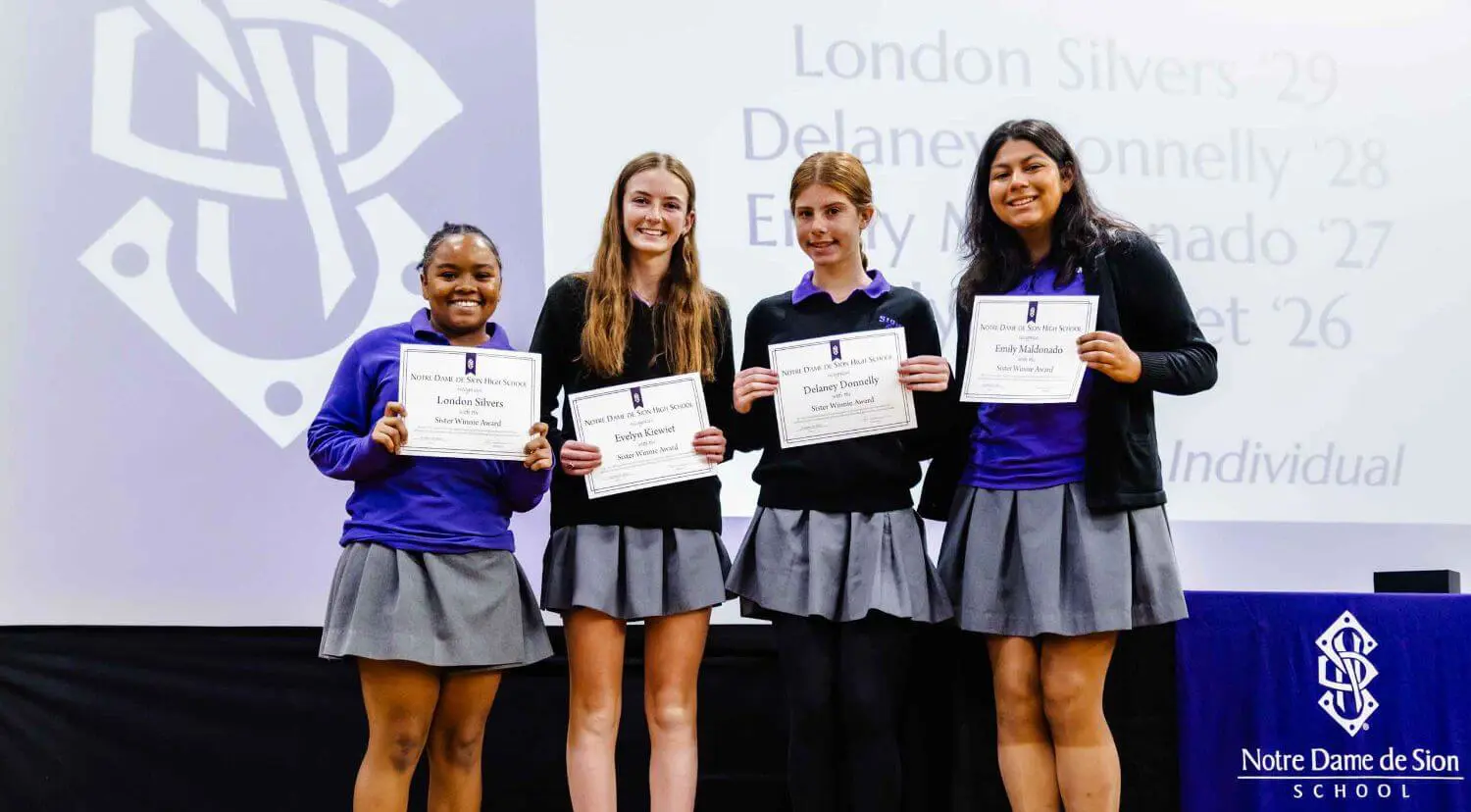 Notre Dame de Sion High School students holding up award certificates.