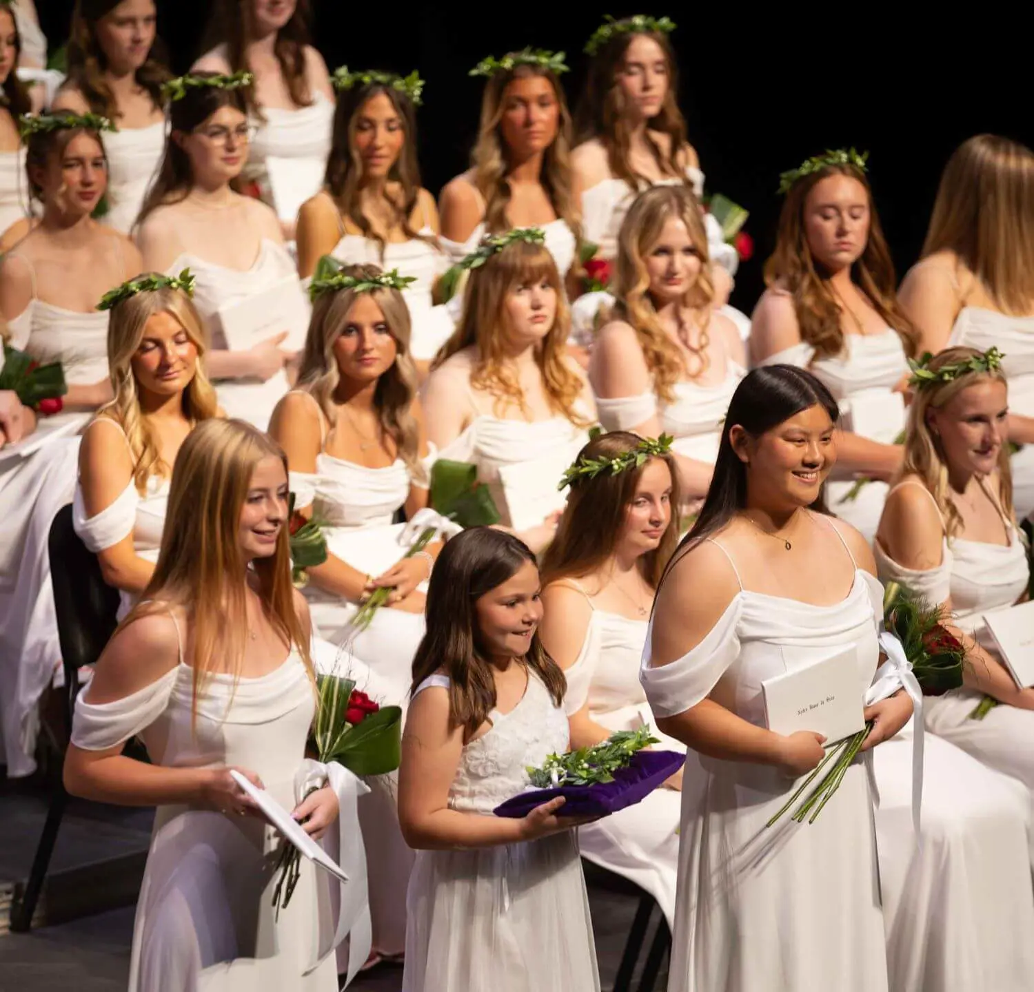 Notre Dame de Sion High School students wearing white dresses and wreathes at graduation ceremony.
