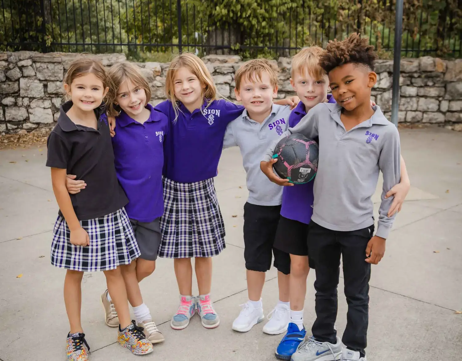 Notre Dame de Sion grade school students in uniform smiling for a photograph.